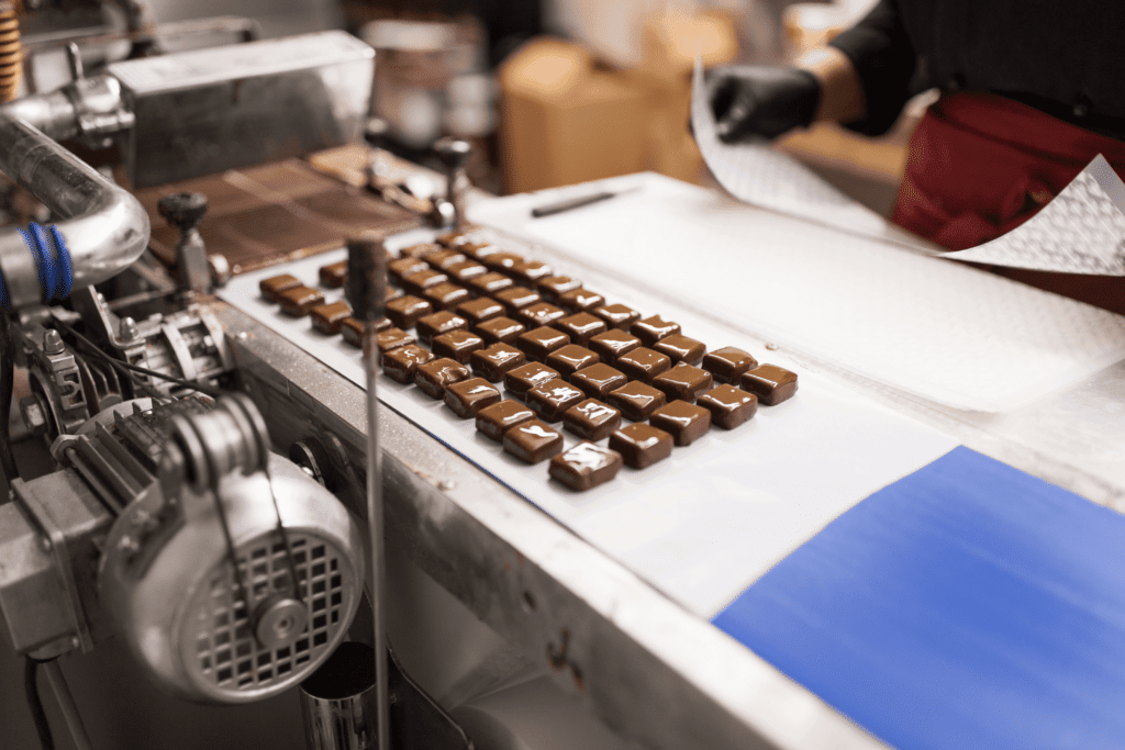 A woman dressed in a protective uniform sorts chocolate on the production line